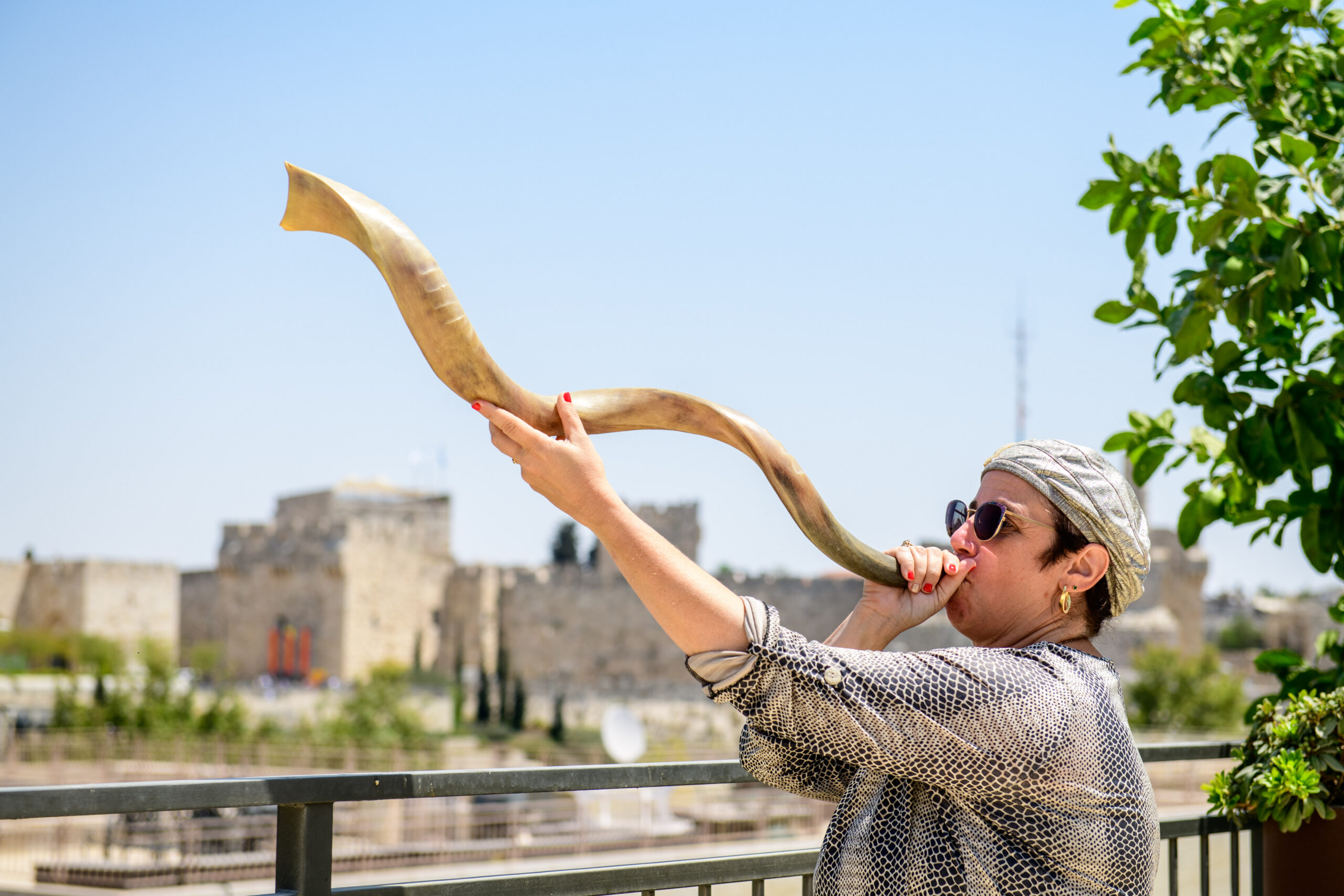 Woman blowing a shofar overlooking the Old City walls of Jerusalem