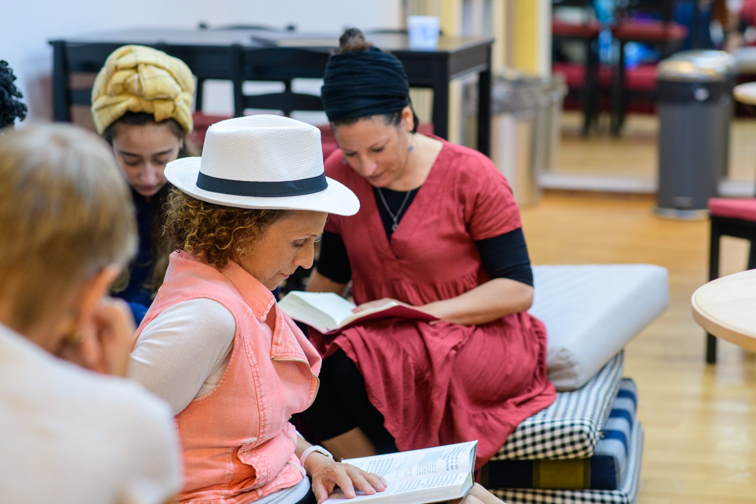 Women reading together from books at a communal study gathering