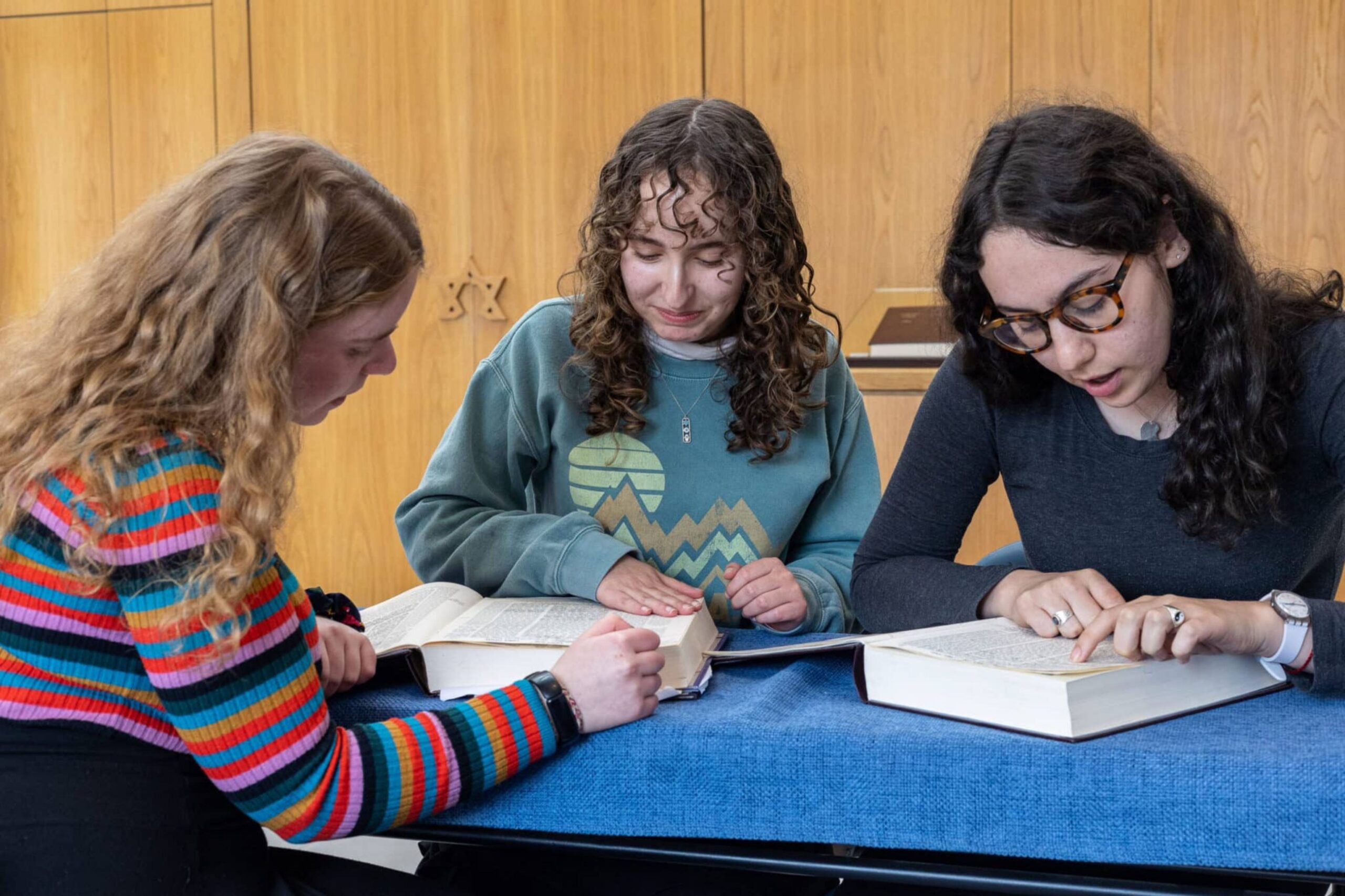 Three young women learning together from open volumes of Talmud