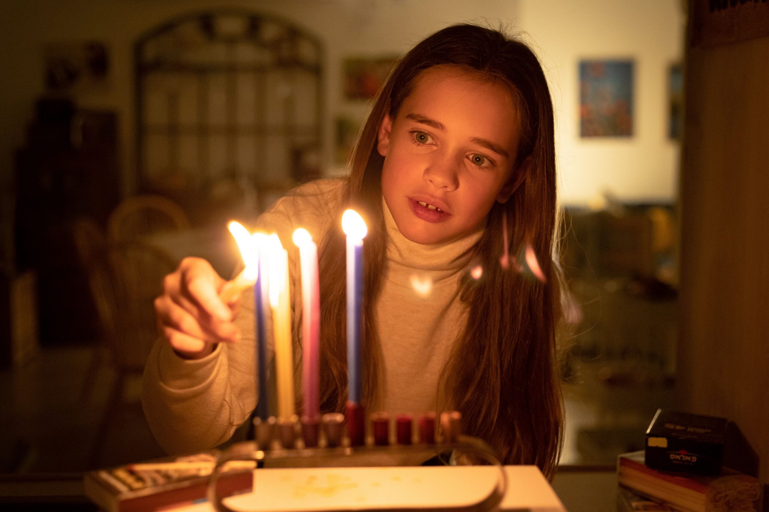 A girl lighting the candles of a hanukkiah
