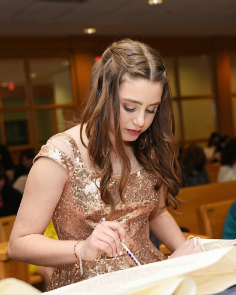 A Bat Mitzvah girl reading from the Torah scroll