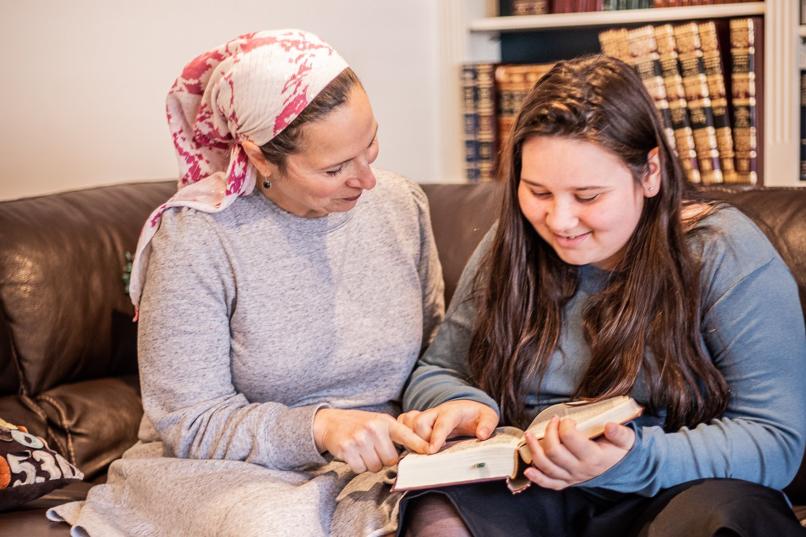 A mother and her daughter learning together from a sefer